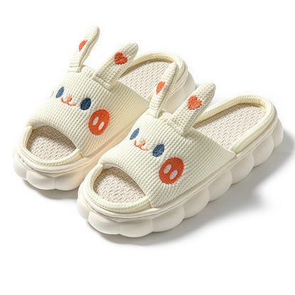 Pair of cream-colored slippers with cartoon face design on a white background