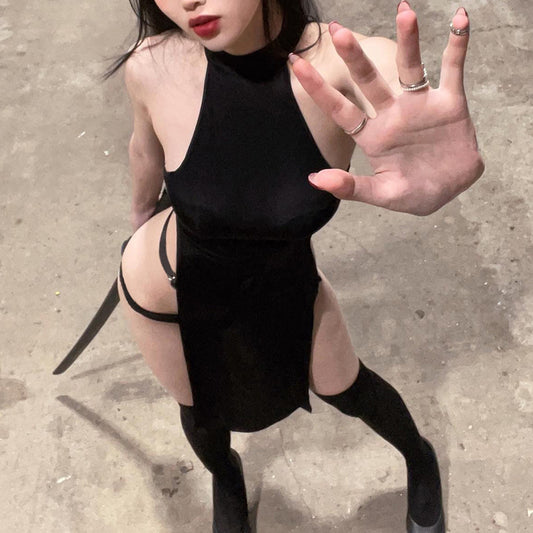 Person wearing a black dress with cut-out design on a concrete surface
