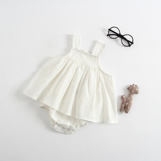 White baby dress with a hair tie and toy on a light gray background