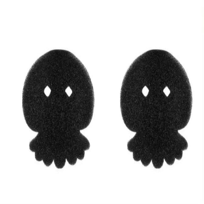 A black sponge shaped like a bear is shown being used to pick up pet hair from a beige surface, demonstrating its use as a cleaning tool.