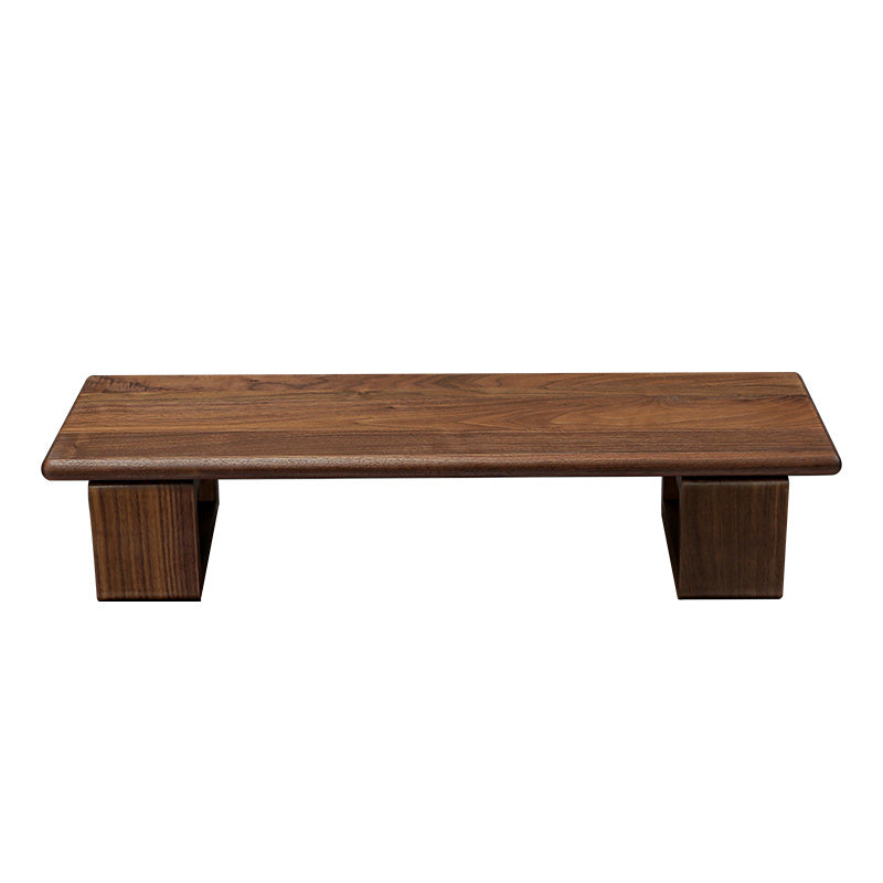 Monitor stand made of black walnut wood, with a computer monitor, keyboard, and various desk accessories on it, placed on a wooden floor against a white background.