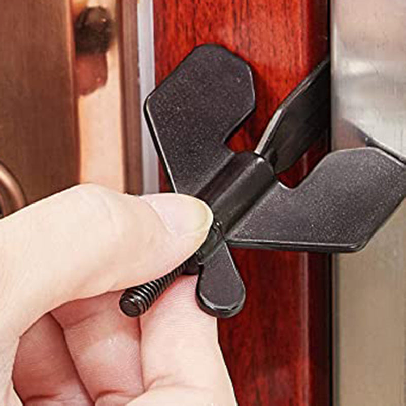 Hand holding a black door stopper against a wooden door