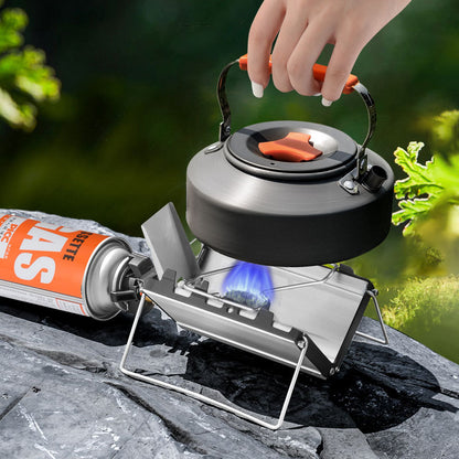 Hand holding a camping kettle over a portable stove with a can of fuel on a natural background