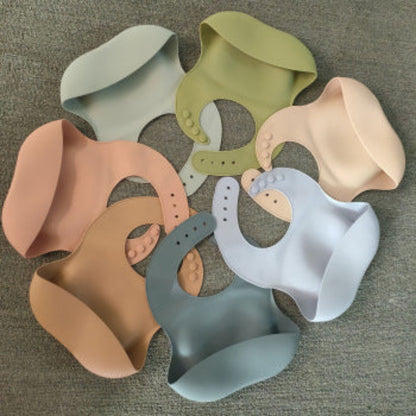 Set of colorful silicone bibs on a textured surface