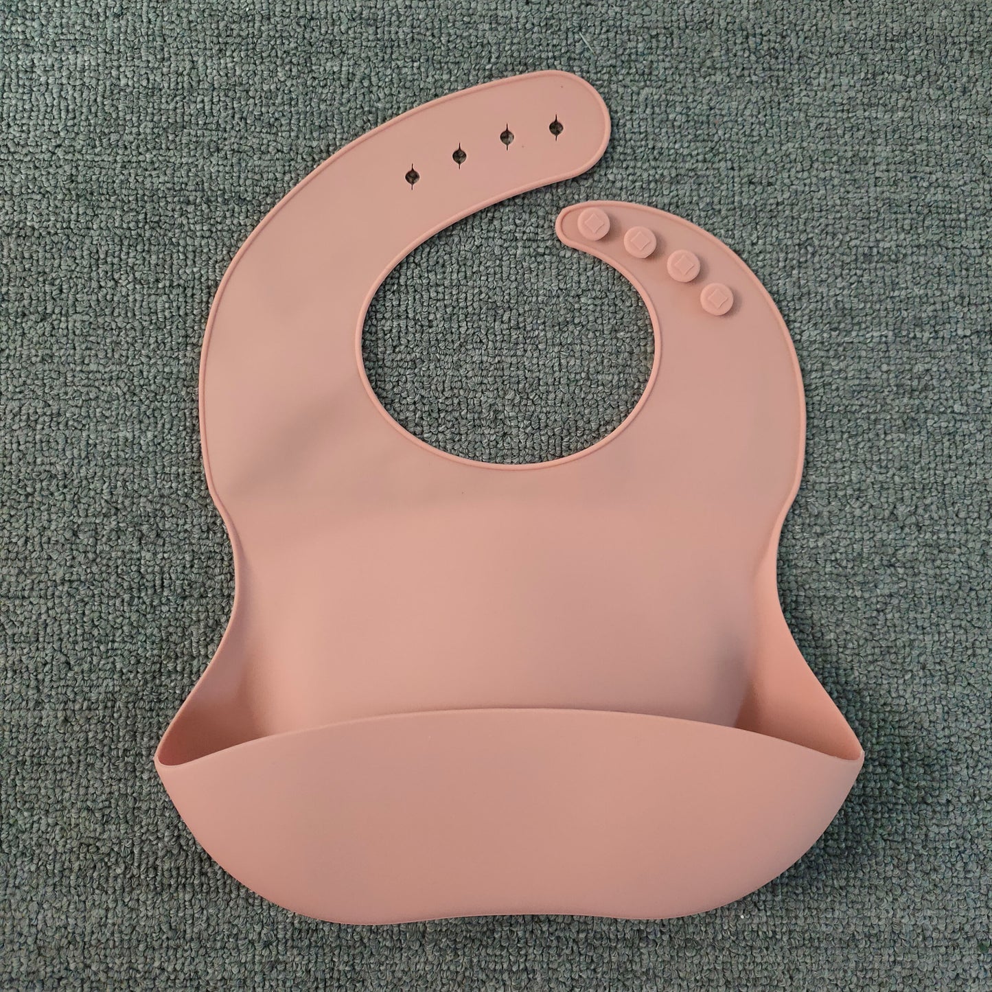Pink silicone bib on a textured gray background