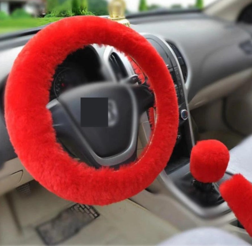 Red steering wheel cover and gear shift knob cover on a car dashboard.