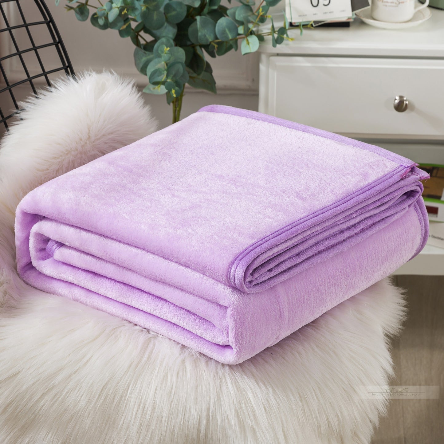 Folded purple blanket on a fluffy white surface.