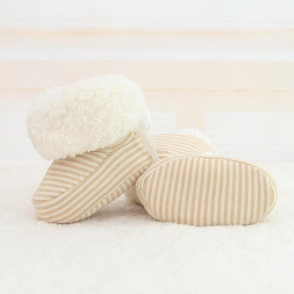 Pair of beige striped baby shoes on a light background
