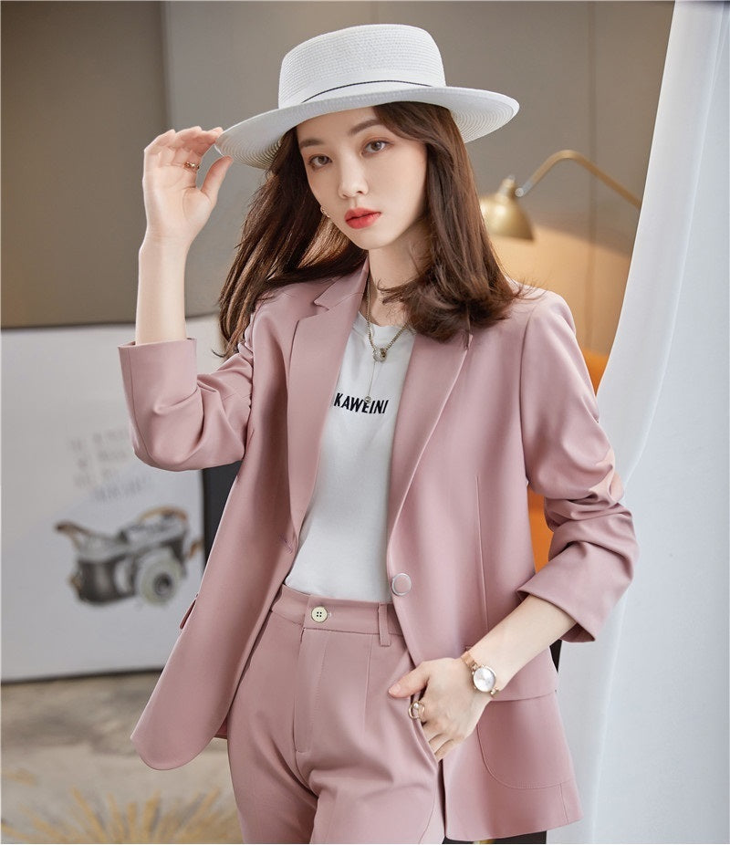 Woman wearing a pink blazer coat with a white hat indoors.
