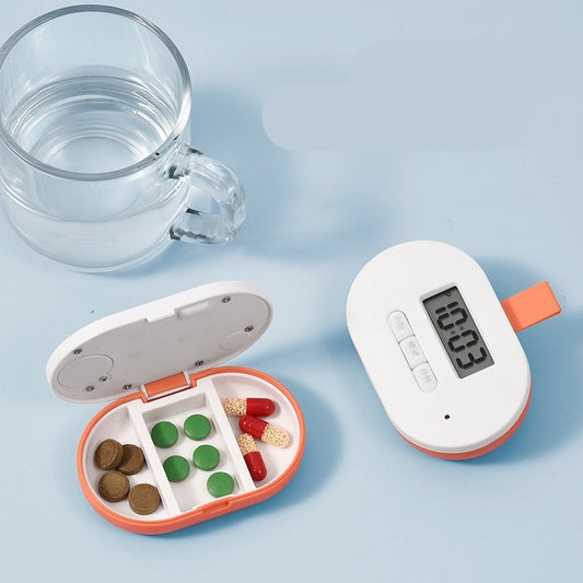 Mini pill box with digital timer next to a glass of water on a light blue background