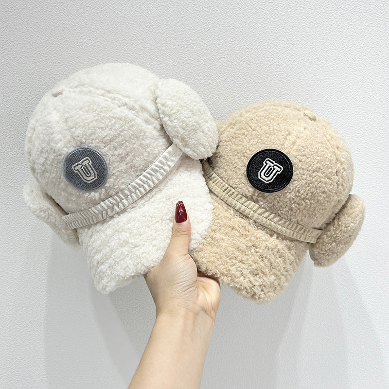 Two plush slippers with ear flaps held by a hand against a white background