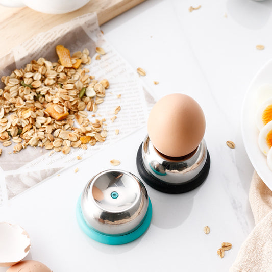 Egg holder with an egg on a white surface with oats and a wooden spoon.