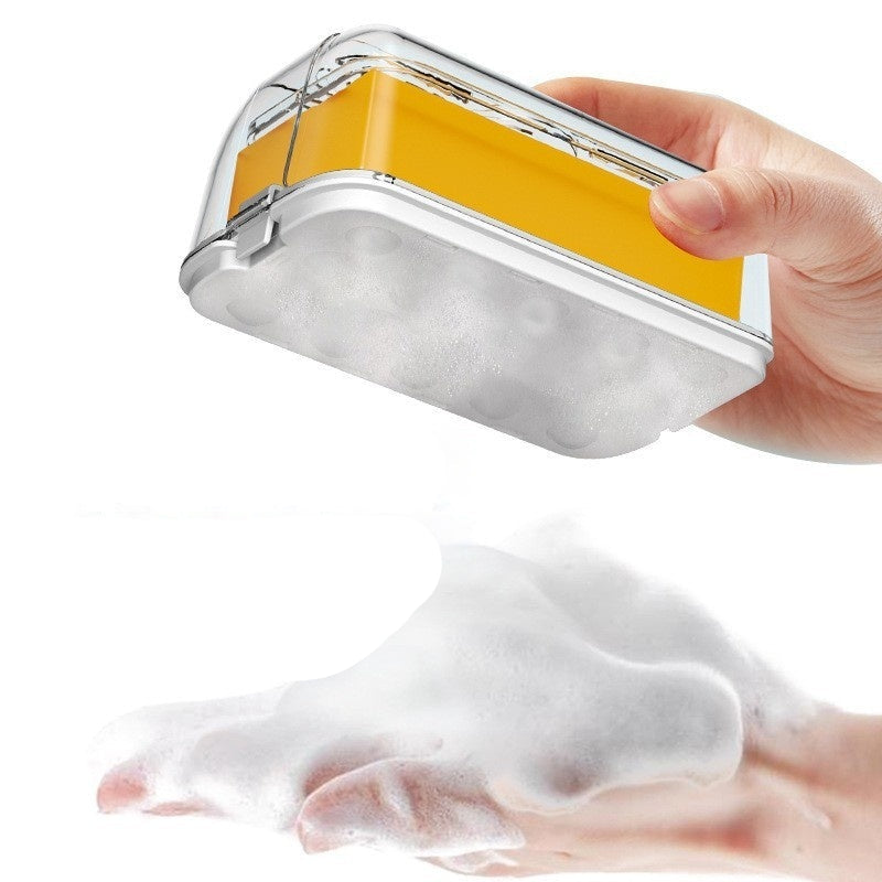 Hand holding a yellow and silver soap container with soapy foam on a white background