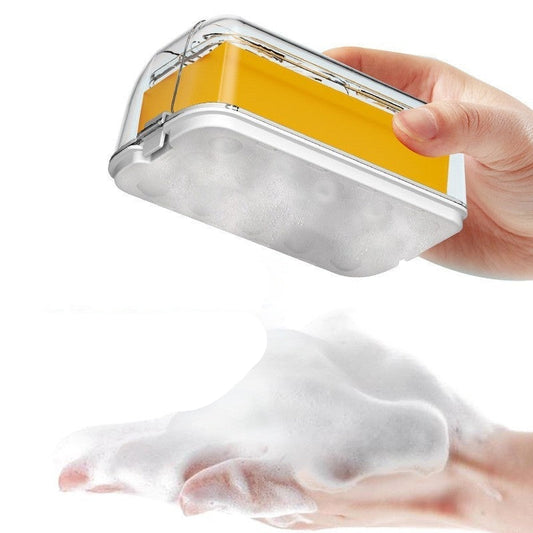 Hand holding a yellow and silver soap container with soapy foam on a white background