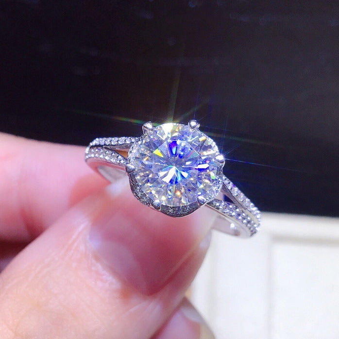 Diamond ring held in a hand with a dark background