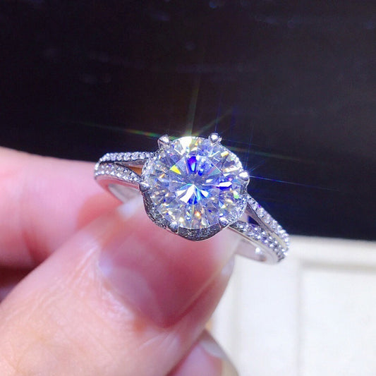 Diamond ring held in a hand with a dark background