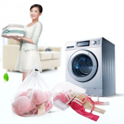 Woman holding clean clothes next to a washing machine with laundry bags on the floor.
