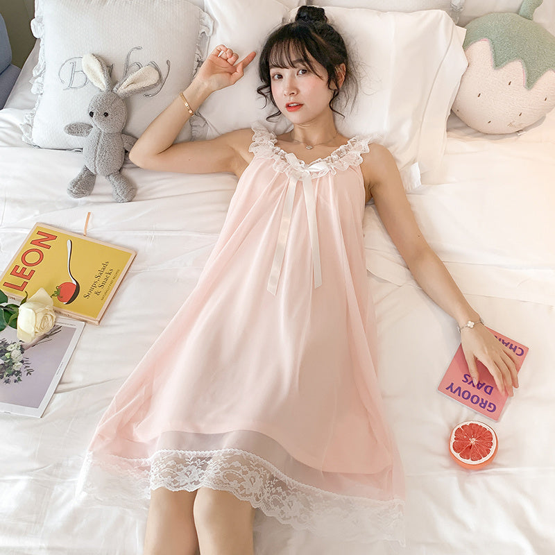 Woman in a pink nightgown lying on a bed with books and a stuffed animal.