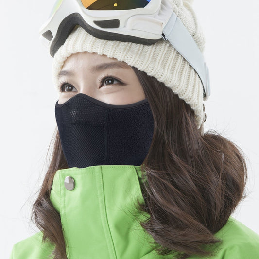 Person wearing a black face mask, white beanie, and green jacket on a light gray background