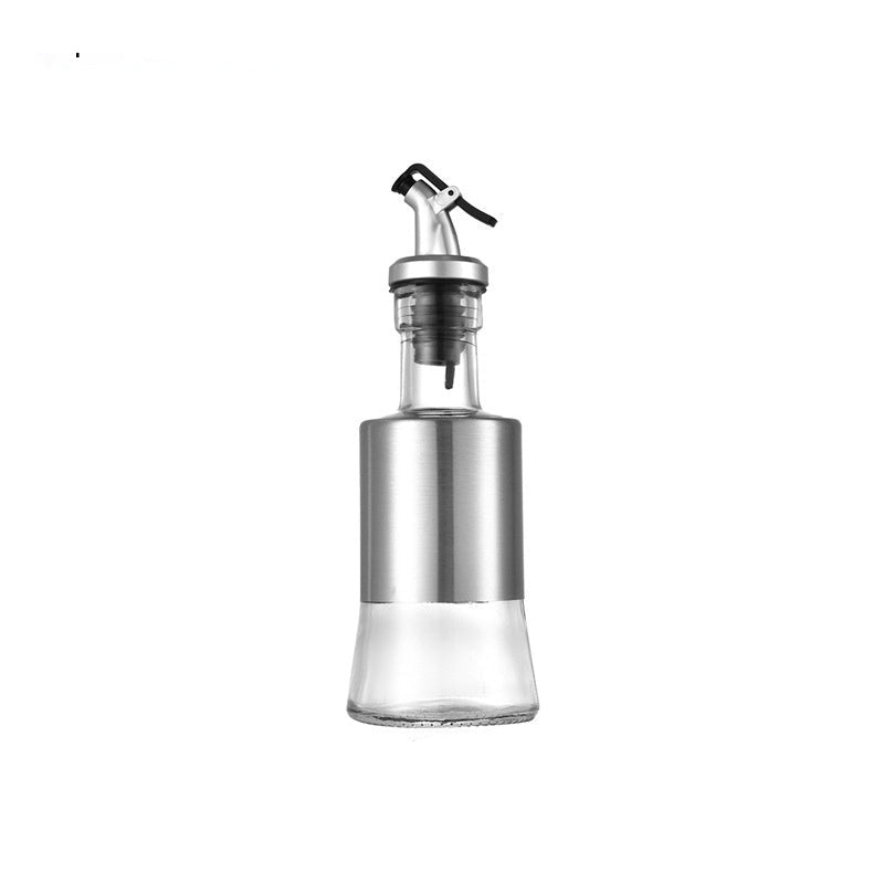 Glass oil dispenser with metal nozzle and measurements on a white background