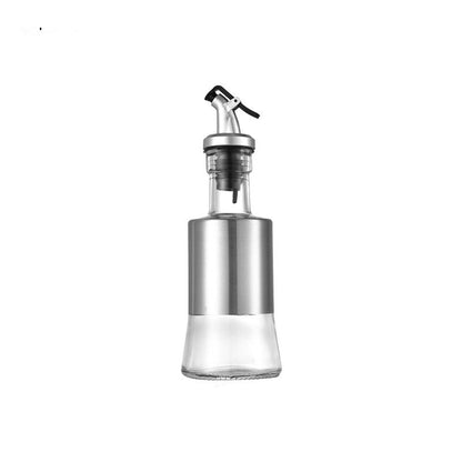 Glass oil dispenser with metal nozzle and measurements on a white background