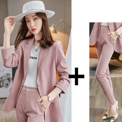 Woman wearing a pink blazer coat and pants with a white hat, standing indoors.