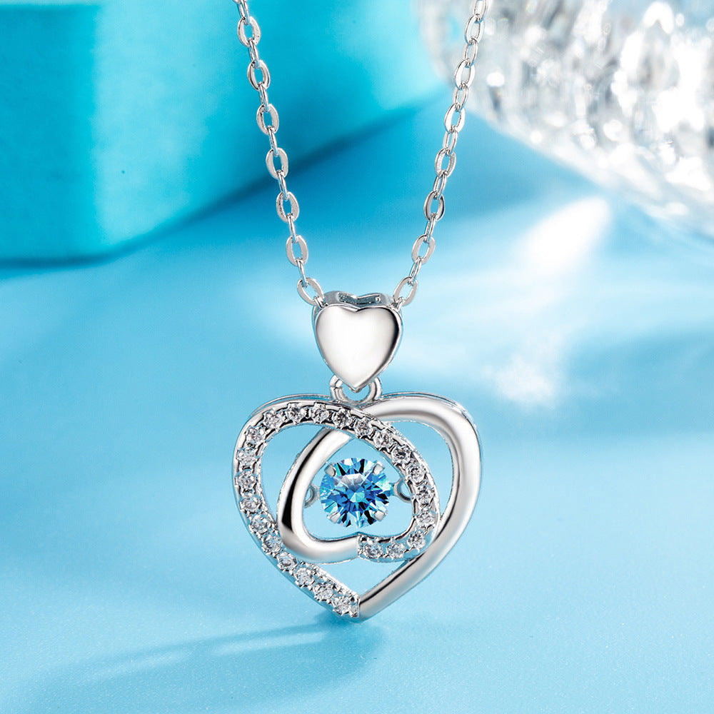 Silver heart-shaped pendant with a blue gemstone on a light blue background