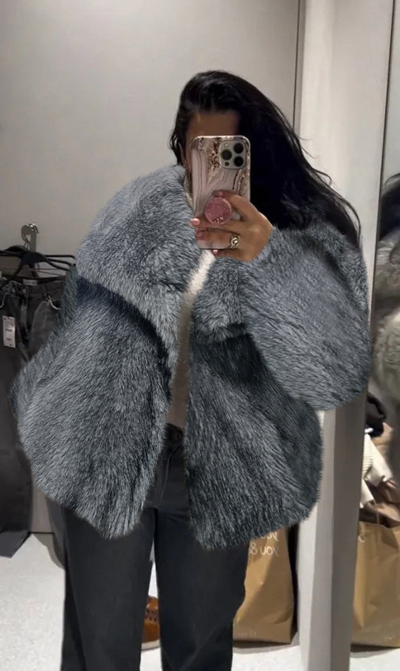 Person wearing a fluffy gray coat taking a mirror selfie.