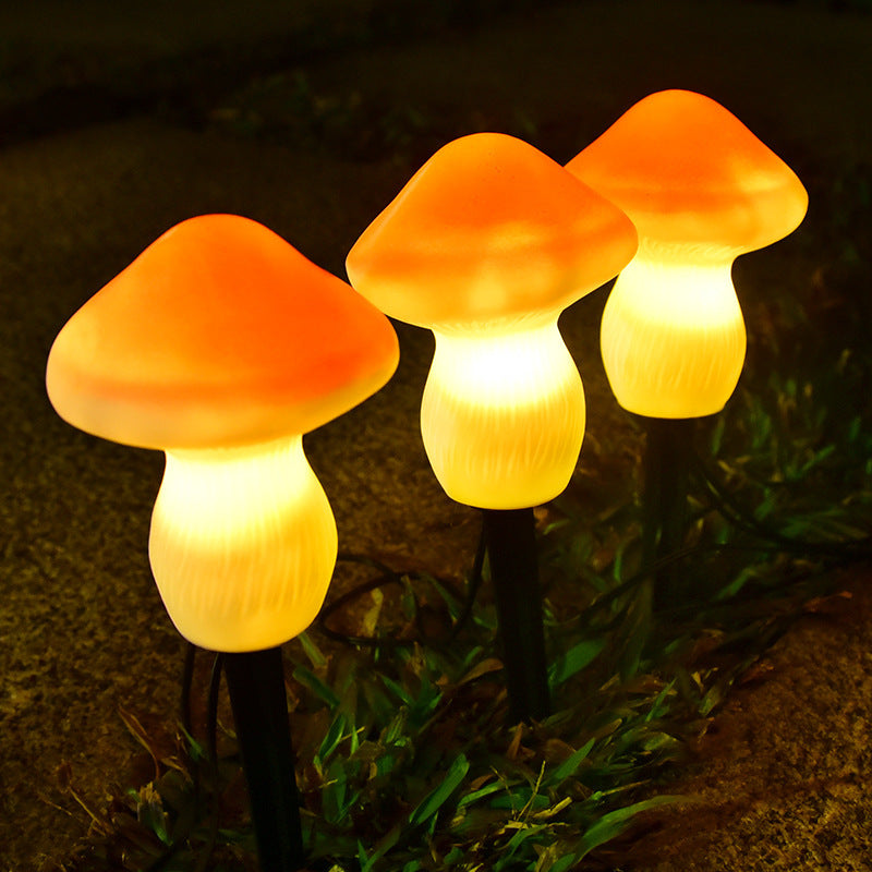 Three mushroom-shaped garden lights glowing in a dark outdoor setting.