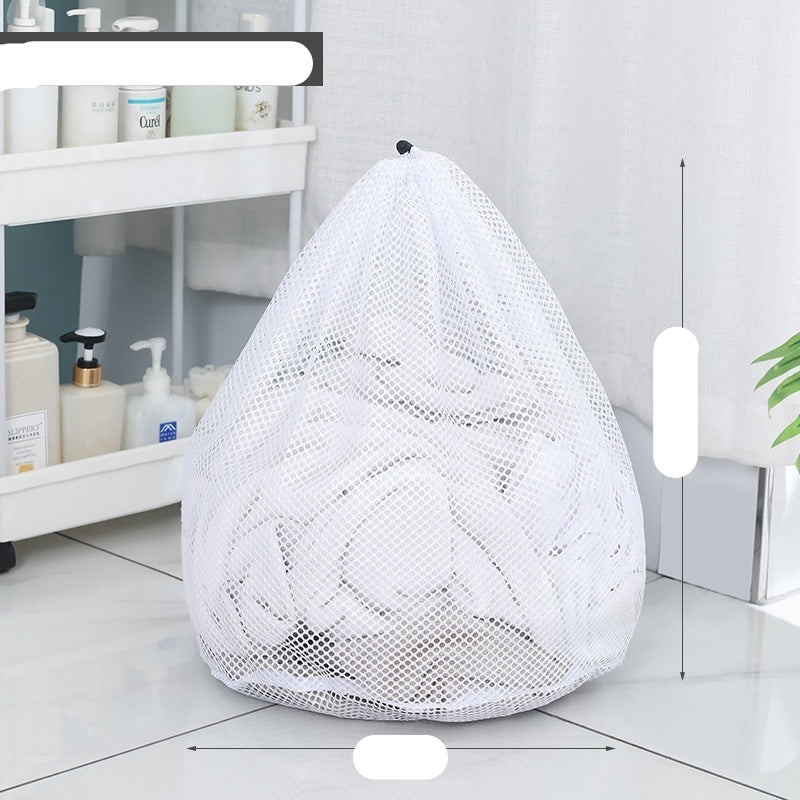 Two white mesh laundry bags filled with laundry standing in front of a washing machine with a person partially visible in the background.