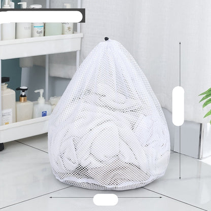 Two white mesh laundry bags filled with laundry standing in front of a washing machine with a person partially visible in the background.