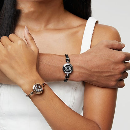 Two wrists wearing elegant bracelets on a neutral background