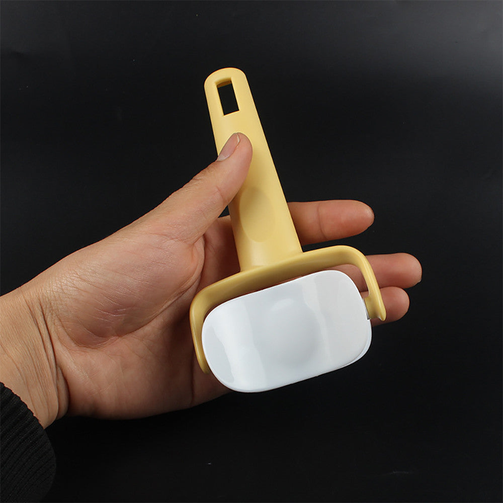 Hand holding a yellow and white cleaning tool against a black background