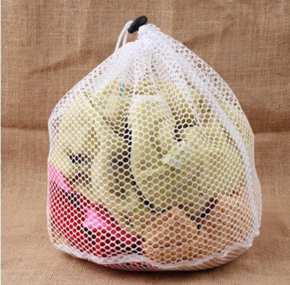 A person holding a white drawstring laundry bag filled with clothes.