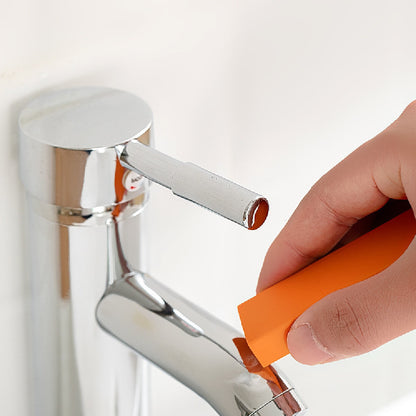 Hand using an orange tool to adjust a silver faucet on a white background