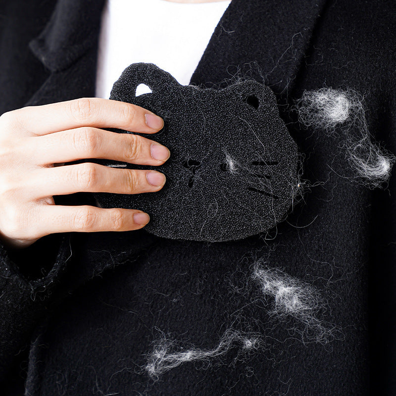 Person holding a black cat-shaped pillow with pet hair on a dark background