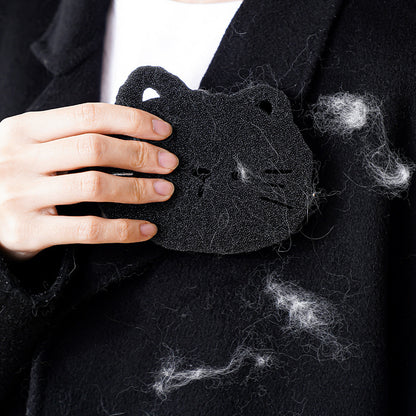 Person holding a black cat-shaped pillow with pet hair on a dark background