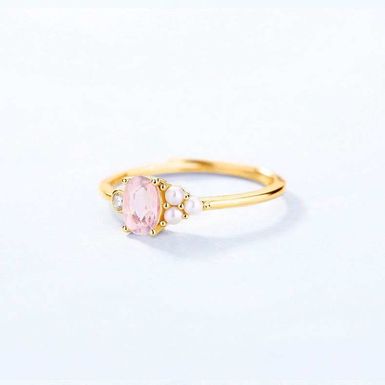 Gold ring with a pink gemstone on a light gray background