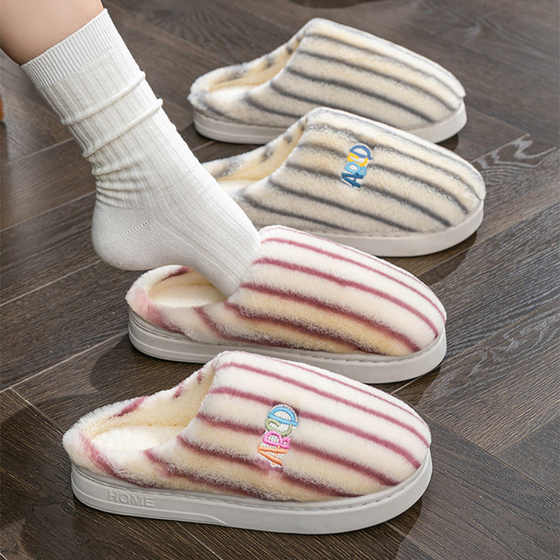 Pair of striped slippers on a wooden floor with a brand logo.