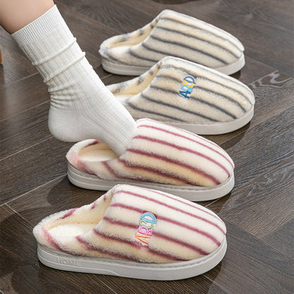 Pair of striped slippers on a wooden floor with a brand logo.