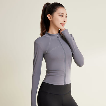 A woman wearing a gray hooded yoga jacket with long sleeves, paired with black workout pants.