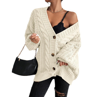 Person wearing a cream cable knit cardigan with buttons, holding a black handbag.
