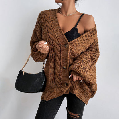 Person wearing a brown oversized knit cardigan holding a black handbag.
