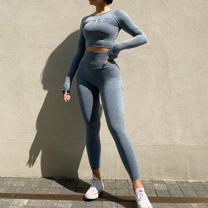 Person wearing a gray athletic outfit standing against a beige wall.
