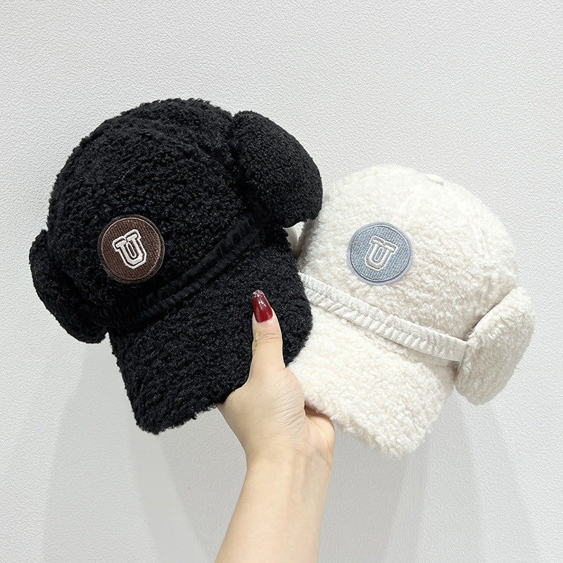 Black and white fleece-lined beanies with ear flaps held by a hand against a light gray background.
