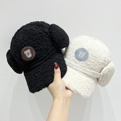 Black and white fleece-lined beanies with ear flaps held by a hand against a light gray background.