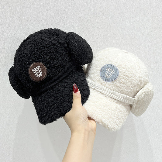 Black and white fleece-lined beanies with ear flaps held by a hand against a light gray background.