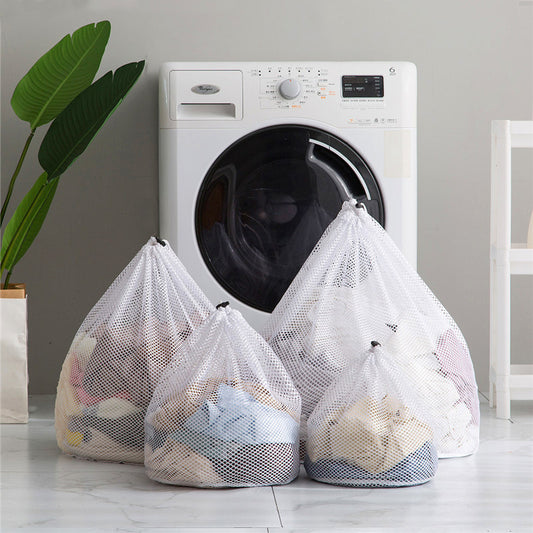 Three different sized clear laundry bags filled with laundry items, placed in front of a washing machine.