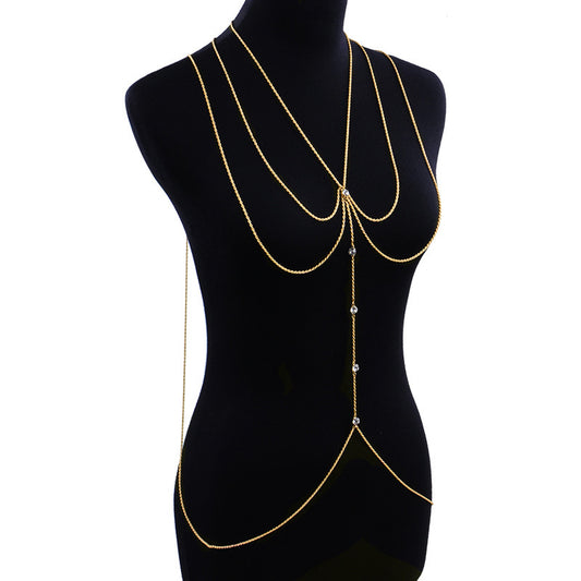 A gold-colored shoulder chain displayed on a mannequin, featuring small clear inlays.