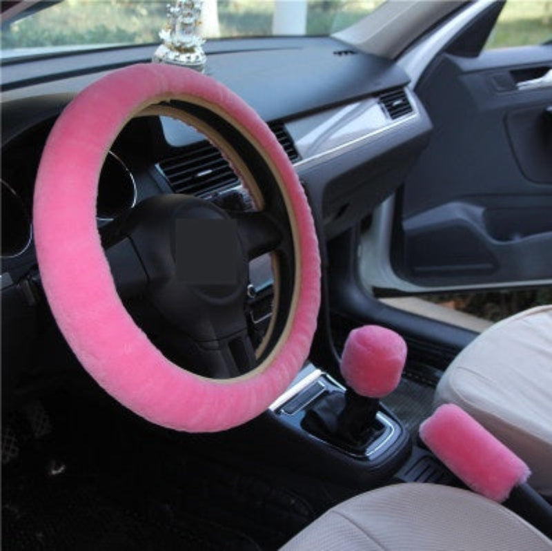 Pink car steering wheel cover and gear shift knob cover set inside a car.